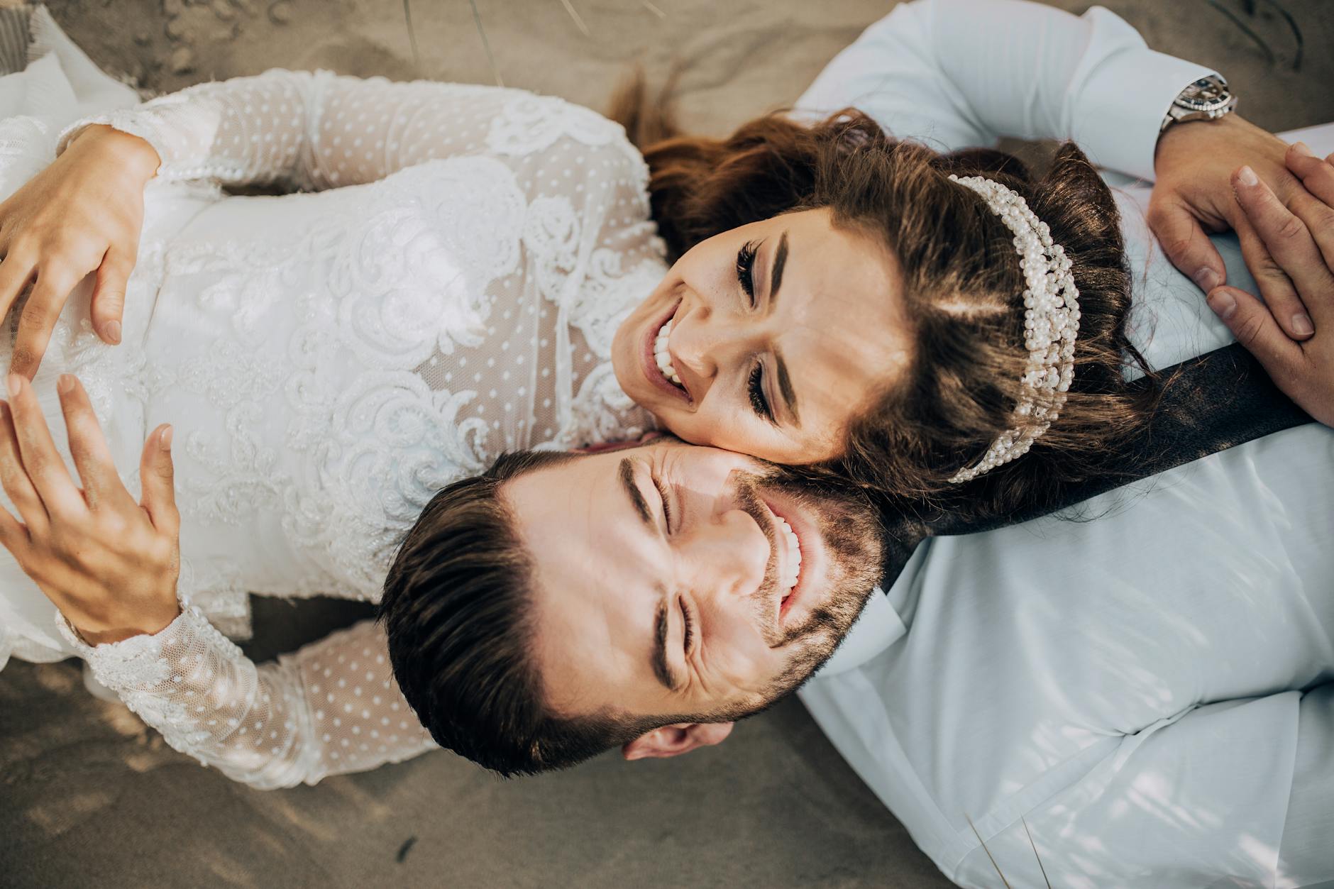 Para młoda w stroju ślubnym leży radośnie na plaży