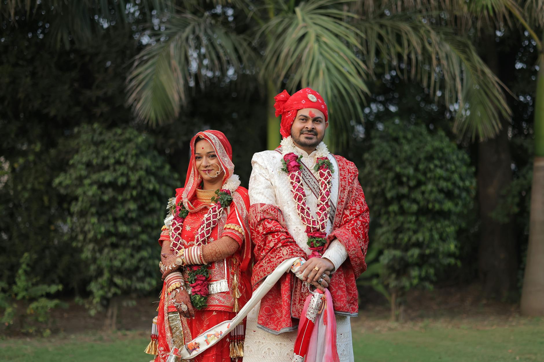 Indyjska para młoda w czerwonych strojach pozuje w plenerze