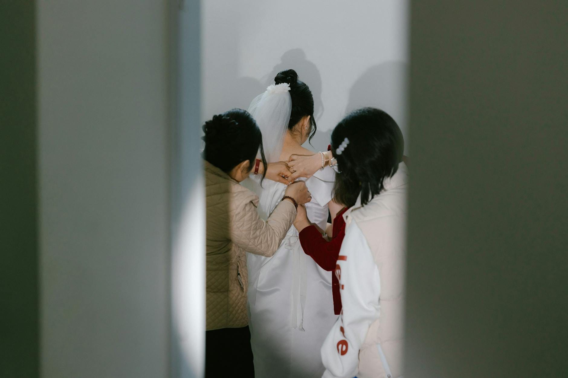 Panna młoda od tyłu szykuje się do ślubu z pomocą druhen